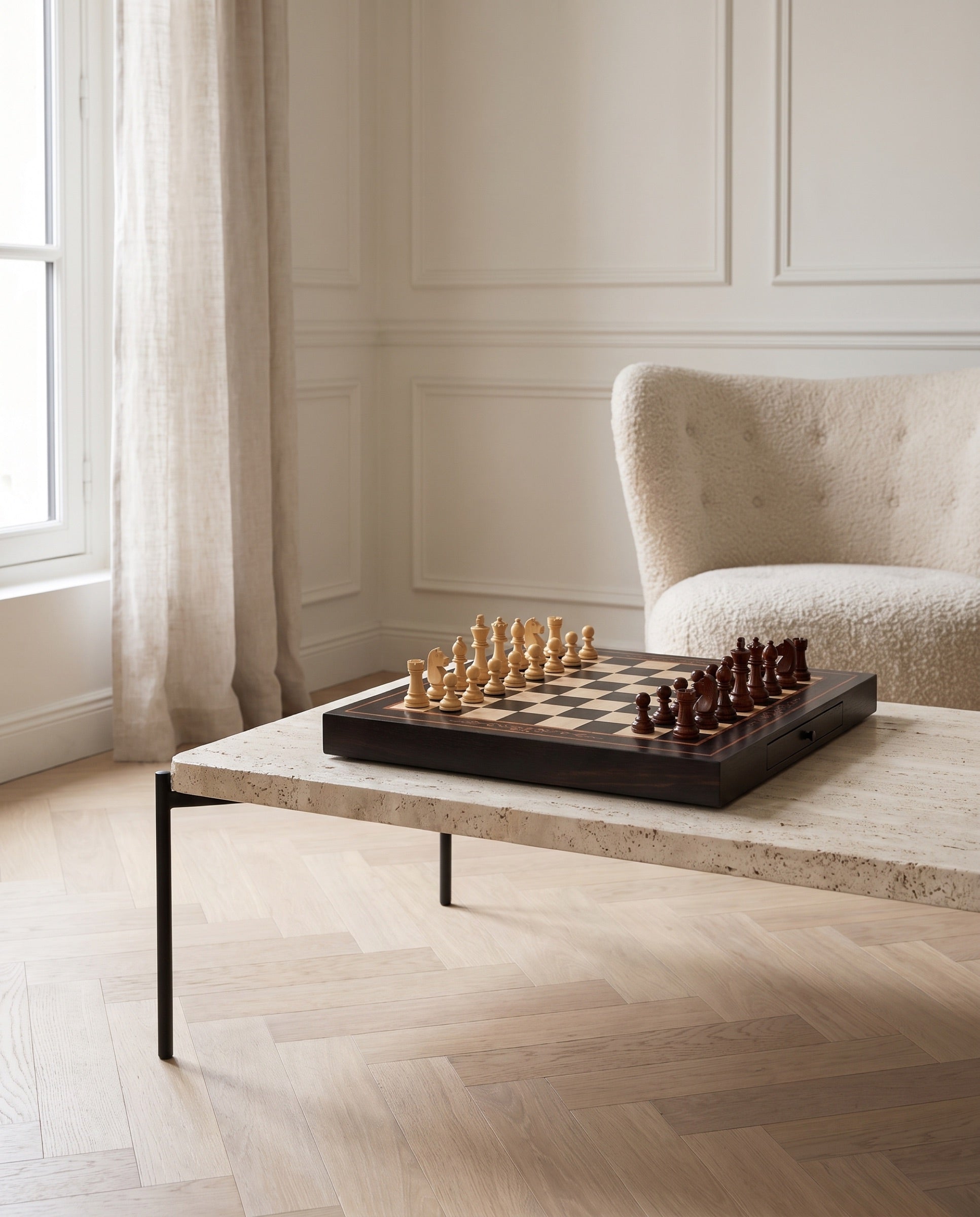 The Duet walnut and maple chess set on a travertine table